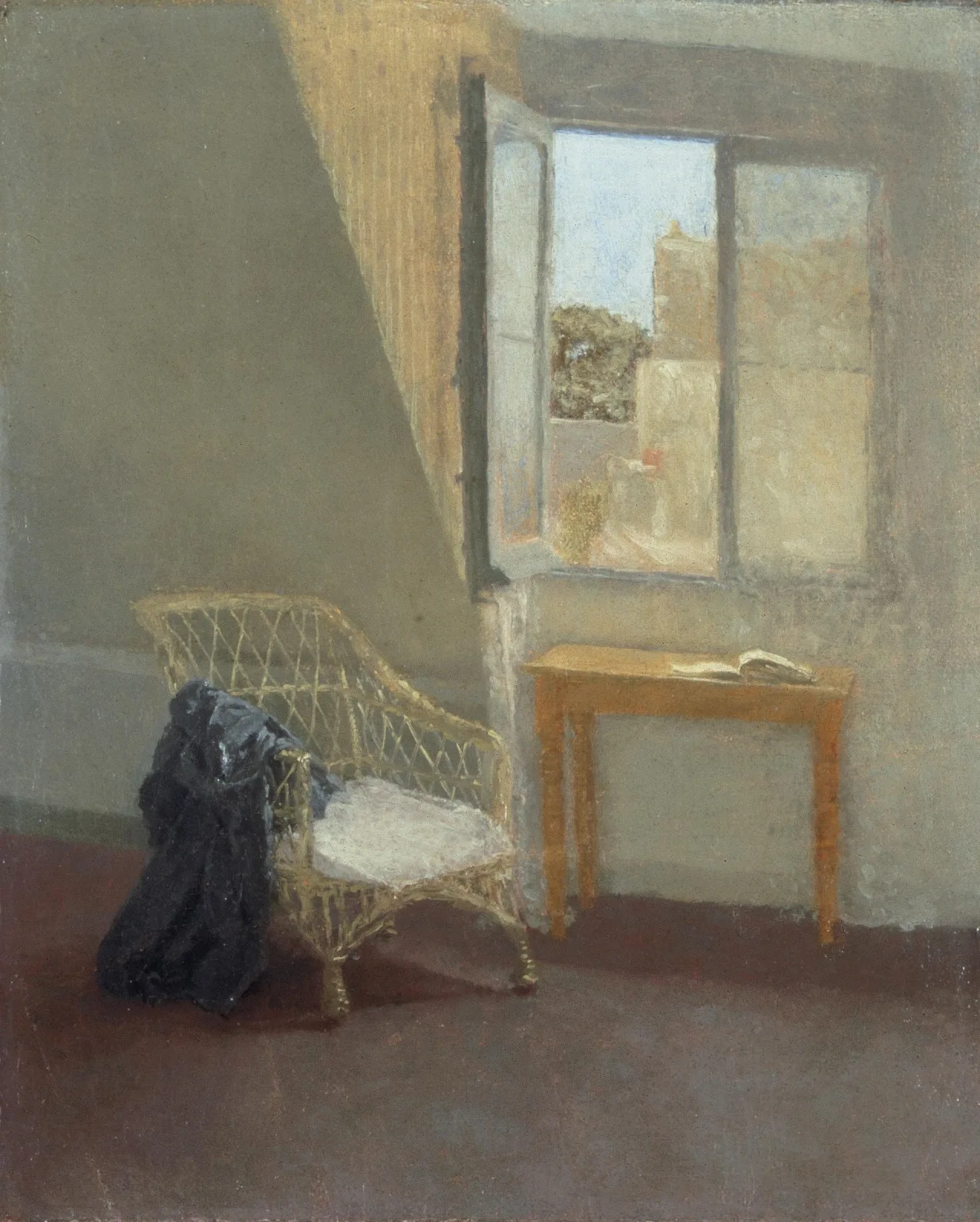 A sparsely furnished attic room with a wicker chair, small table, open book, and half-open window